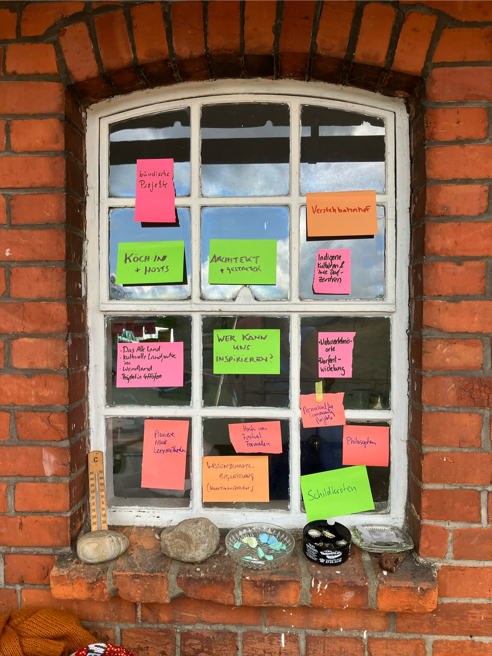Weißes Sprossenfester in Backsteinwand mit bunten Post-its auf der Scheibe