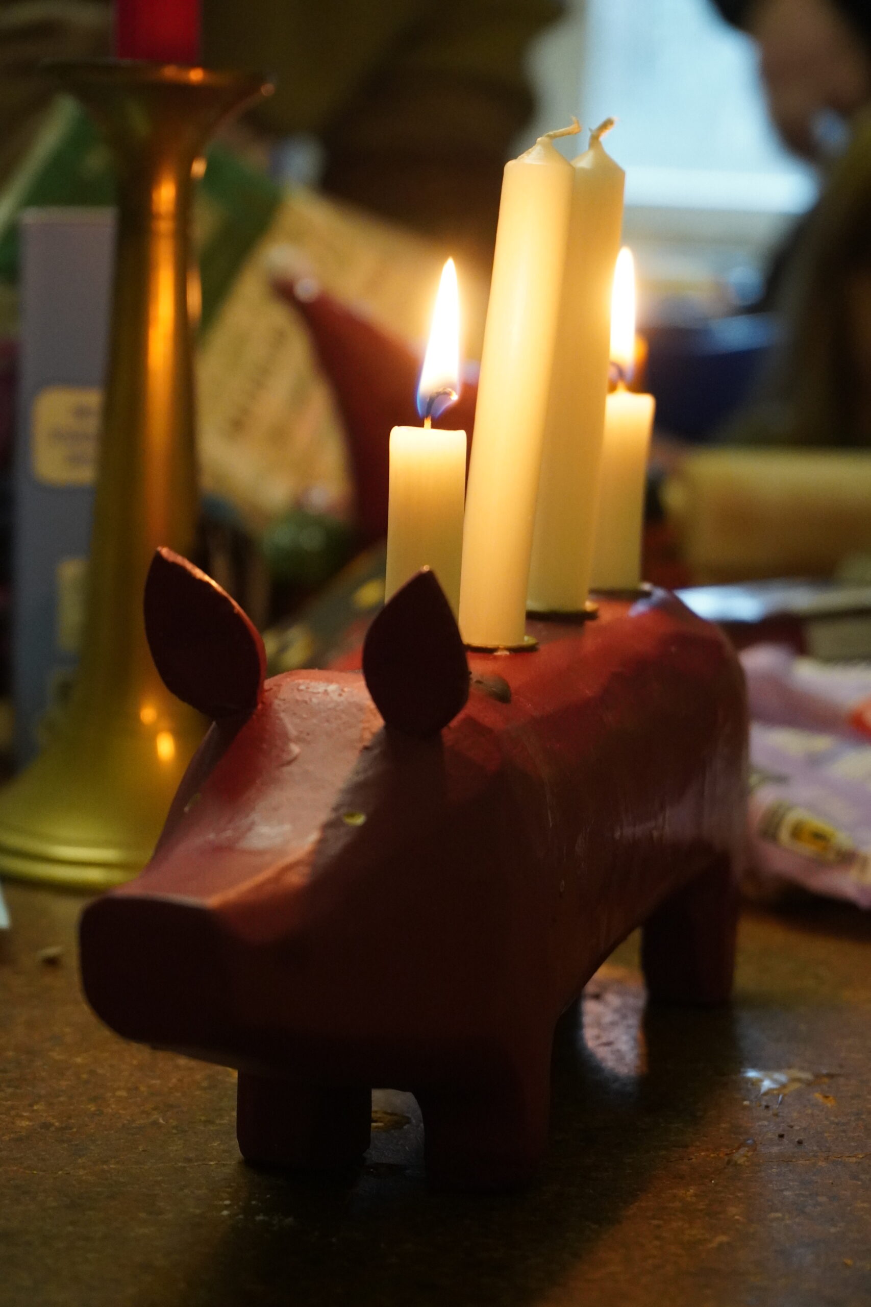 Ein Adventsschwein mit brennenden Kerzen auf dem Tisch